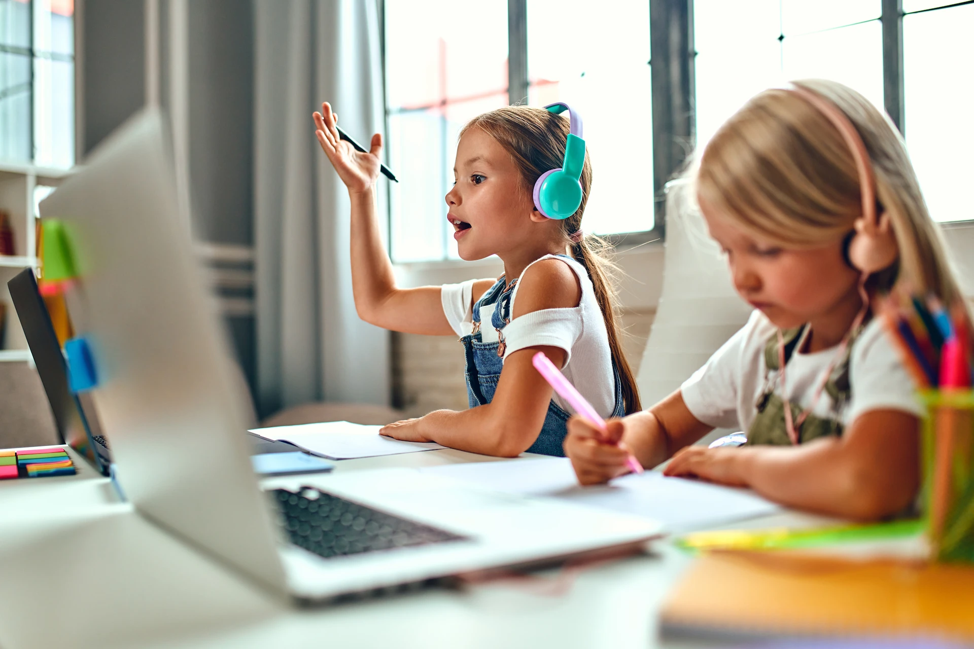 2 young students working at their desk and laptops with headphones on