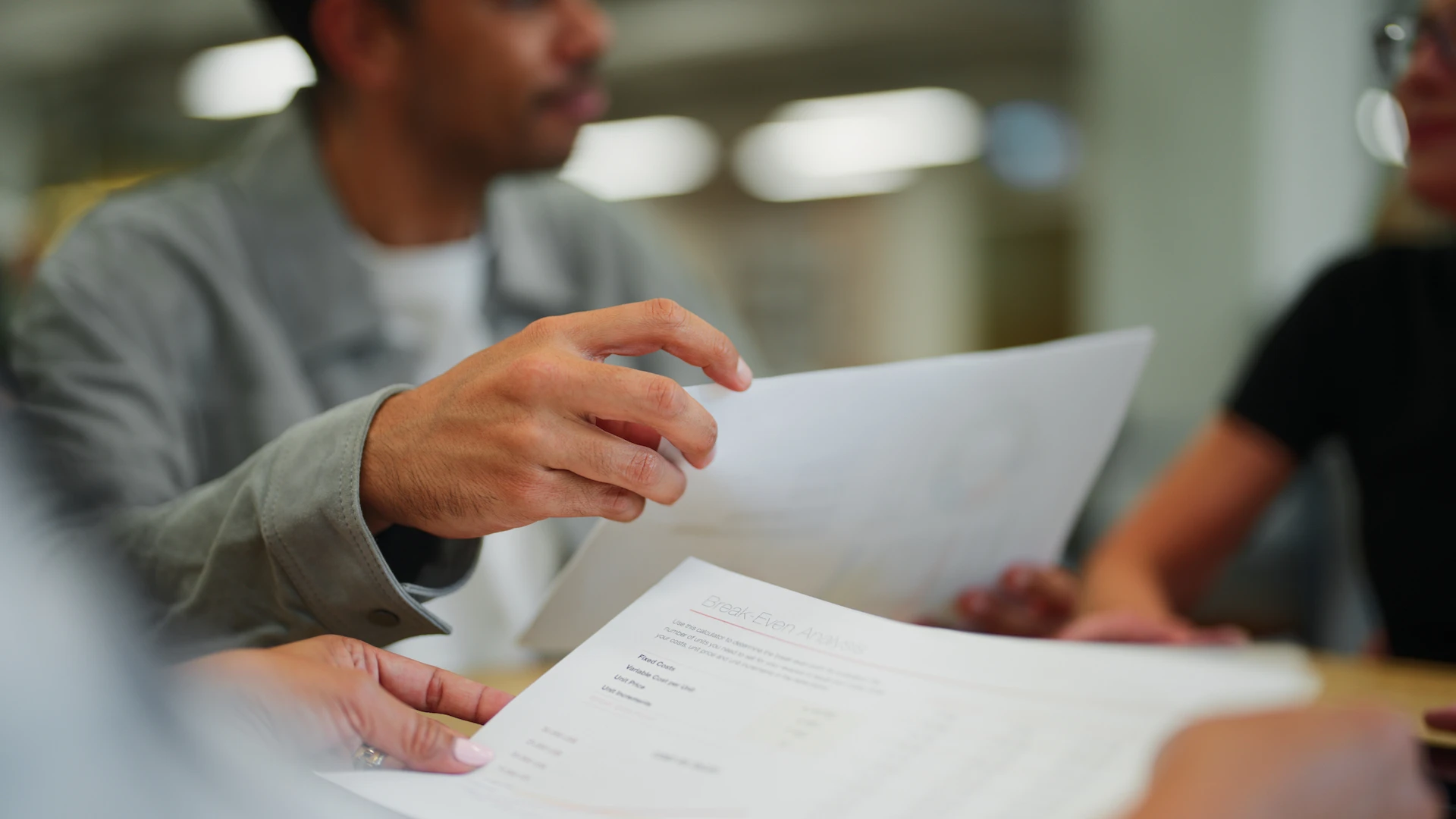 administrators in a meeting at a conference table holding and shuffling paperwork